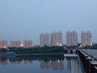 傍晚，我們騎車又來到這里。天色陰暗，整個天空被大霧籠罩，看不到明月與星辰，內心也好似蒙塵。坐了一會兒，已沒有雅興觀賞，往返途中，回頭一望，遠處高樓聳立，樓頂上紅色燈火映在水面上形成一道光束，猶如落日余暉灑在水面上，紅彤彤，金燦燦地，絢爛奪目，水面上依然波光如鏡。驀然心里注入一道光，當你的視覺僅停留在灰色地帶，就難以發現生活的那抹亮色，當你轉念一想，其實好景就在那里，你注意到它，它就給你點亮心情。你看那水，縱然外面煙霧繚繞，我自水波不興，風平浪靜。配圖