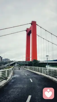 阴云笼罩的午后，沿着滨江步道慢慢前行。笔直路面一路延伸，视线定格在醒目的红色桥塔。
人偶尔该如蜻蜓穿梭市井，不必时刻紧绷赶路。撞见心动风景，便停下脚步留存片刻安宁。
长期倾听别人心事才懂得，大多焦虑都因为走得太急。适当放慢节奏，和日常温柔和解，浮躁内心，终能寻得安稳。配图