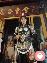 《杨柳青古巷遇戎装赋》
 
暮临津沽杨柳青墟，长街灯华，古肆连楹。余闲步漫游，忽见一戎装少年立巷隅，玄铠鎏纹，长戈倚侧，眉目疏朗，英气凌云。金甲映霓虹，身姿挺拔若青松临风，顾盼之间，俊采飞扬，令人目移心喜。
 
余趋前相与语，言欲留影纪此相逢。少年温雅谦和，闻言欣然颔首，俯仰立坐，皆顺人意，摆姿展态，毫无倦怠，待人以诚，气度温润，初见便觉心头烦扰消解大半。方调镜头之际，一家四口缓步而至，远客夫妻携两稚子，远道来游古镇。夫君执机欲为妻取景，持镜茫然，不知章法。余侧立旁，细教取景光影、身形站位之法，嘱其寻温柔姿态衬佳人风姿。
 
其夫闻言莞尔，回身笑语妻曰：“无妨，可依偎相拥，随心喜乐，不必拘谨。”语罢伸手相挽，妻霎时展颜，笑靥如花，眉眼间羞怯尽散。身旁两童见状，亦拍手嬉闹，绕膝奔走，满是童真烂漫。少顷夫君移步上前，自请立镜前，摹美猴王腾跃之姿，抬手探额，嬉闹无拘，阖家笑语充盈古巷。
 
余立旁静观，心下慨然。此一家四口，夫知惜妻，妻善解意，稚童无忧，彼此体恤成全，无隔阂拘束，方是华夏家庭本真之温情。尘世奔波，世人常困于疏离、苛责，心有郁结，难寻松弛暖意。今古镇灯火、飒爽少年治愈尘俗疲惫，更得此和睦阖家涤荡心绪，恍然知晓治愈本心者，从非远在山海，乃是人间相守的松弛与包容。
 
戎装少年以谦和待人，予过客温柔；寻常夫妇以坦诚相待，予彼此欢愉。烟火古巷，铠甲英姿衬阖家温情，一静一动，皆是人间至善光景。愿九州万户皆如此：夫妻相知不藏拘谨，亲子相伴常存欢颜，家人之间随心抒意，彼此成全，相守和乐，岁岁常有笑语相伴，岁岁皆得温柔治愈。世间万千烦忧，皆可在家人松弛暖意里缓缓消融，人间至幸，莫过于阖家自在，心无芥蒂，喜乐常随。配图