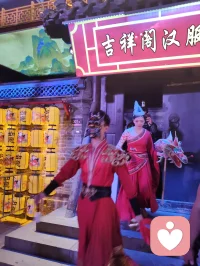 柳青古巷观群伶赋！
津沽之西，杨柳青墟，华灯千叠，古肆纵横。余夜踏长街，入汉服雅馆，见诸伶衣袂纷纭，百态纷呈，恍若穿越千年京华。
有宫娥红罗曳地，步缓腰柔；萨满彩衣缀饰，古韵苍然；财神锦袍鎏金，笑意温厚；龙袍帝者端立，却无半分矜傲。余趋前请其展姿，帝王欣然舒袖，执扇斜倚，俯仰随吾心意，平易可亲，全无居高之态；八戒扮相憨然敦厚，待人温和，观之使人忘忧。
更有一舞姬，素袖翻飞，身轻似燕，踏光旋舞，一颦一动皆藏风月。余伫立观舞，尘心烦扰尽数消散，心旷神怡，文思奔涌，倚兴挥毫，顷刻成赋，递与佳人。彼展卷细读，眼含温柔，浅笑揖别，眉眼盈盈，相逢之喜，溢于眉宇，此乐难言，美哉甚哉。
 
余素怀三境之心：持儒者赏美之温，怀释者渡人之善，存道者随性之旷，恰似柳七流连市井，不束于俗规，乐于观人间风月、赏众生清妍。世间多困于自我内耗，鲜少静心欣赏旁人光彩，殊不知赞美本是双向治愈。予人一眼欣赏，赠人一纸诗文，一份赤诚欢喜流转彼此心间，愁绪自消，暖意自生。
此间伶人各有风姿，不掩各自本真；往来游人各怀心事，皆可借古巷风情抚平褶皱。帝王放下威仪，舞姬舒展柔姿，财神藏起世俗功利，戏偶褪去扮演隔阂，人人卸下紧绷防备，松弛自在，便是人间最好疗愈。
不必高居庙堂寻清欢，不必遁入深山求心安，市井灯火、衣袂翩跹、相逢一笑、提笔成篇，皆是治愈良方。以坦荡心赏世间美，以温柔意传人间爱，随遇而安，随性抒怀，儒释道相融于心，在烟火长巷中寻得自在真我，把细碎欢喜赠予相逢之人，便是此生通透洒脱。配图