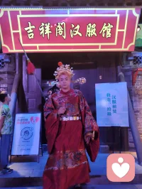 柳青古巷观群伶赋！
津沽之西，杨柳青墟，华灯千叠，古肆纵横。余夜踏长街，入汉服雅馆，见诸伶衣袂纷纭，百态纷呈，恍若穿越千年京华。
有宫娥红罗曳地，步缓腰柔；萨满彩衣缀饰，古韵苍然；财神锦袍鎏金，笑意温厚；龙袍帝者端立，却无半分矜傲。余趋前请其展姿，帝王欣然舒袖，执扇斜倚，俯仰随吾心意，平易可亲，全无居高之态；八戒扮相憨然敦厚，待人温和，观之使人忘忧。
更有一舞姬，素袖翻飞，身轻似燕，踏光旋舞，一颦一动皆藏风月。余伫立观舞，尘心烦扰尽数消散，心旷神怡，文思奔涌，倚兴挥毫，顷刻成赋，递与佳人。彼展卷细读，眼含温柔，浅笑揖别，眉眼盈盈，相逢之喜，溢于眉宇，此乐难言，美哉甚哉。
 
余素怀三境之心：持儒者赏美之温，怀释者渡人之善，存道者随性之旷，恰似柳七流连市井，不束于俗规，乐于观人间风月、赏众生清妍。世间多困于自我内耗，鲜少静心欣赏旁人光彩，殊不知赞美本是双向治愈。予人一眼欣赏，赠人一纸诗文，一份赤诚欢喜流转彼此心间，愁绪自消，暖意自生。
此间伶人各有风姿，不掩各自本真；往来游人各怀心事，皆可借古巷风情抚平褶皱。帝王放下威仪，舞姬舒展柔姿，财神藏起世俗功利，戏偶褪去扮演隔阂，人人卸下紧绷防备，松弛自在，便是人间最好疗愈。
不必高居庙堂寻清欢，不必遁入深山求心安，市井灯火、衣袂翩跹、相逢一笑、提笔成篇，皆是治愈良方。以坦荡心赏世间美，以温柔意传人间爱，随遇而安，随性抒怀，儒释道相融于心，在烟火长巷中寻得自在真我，把细碎欢喜赠予相逢之人，便是此生通透洒脱。配图
