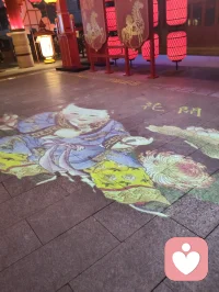 青石板铺展流动光影，游鱼逐光、莲荷静绽，立体彩蝶灯栖于巷侧。心理学提出，动态柔和的视觉画面可分散精神焦虑，使人从繁杂思绪抽离。缓步踏过流光，视线随锦鲤轻游，紧绷心绪慢慢松弛，虚实相融的夜景，成为治愈心灵的温柔容器。配图