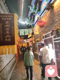 古巷香韵风物赋！
 
津沽杨柳青长街，夜色铺陈，百家风物分列檐下。有戏曲冠冕绮丽敷彩，香肆悬“天佑合香”匾额，古法香囊满架垂芳，瑞狮摆件藏民俗喜气，木牌箴言静立门扉，繁花灯影缀满檐角。
 
观诸风物：凤冠珠翠层叠，映红光而蕴雅致；合香囊纳草木清芬，一嗅便涤荡尘浊；木牌镌素简哲语，字句温润安抚心绪；瑞狮藏市井吉意，艳色消人沉郁。一街之间，声色香韵俱全，目之所遇皆民俗温柔，鼻之所闻皆草木清宁。
 
心理学云，多感官治愈最能疏解内耗。目赏绮丽冠饰、暖巷灯火，鼻纳天然古香，心品简约箴言，多重温和感知层层包裹心神。平日缠身的焦虑紧绷，随香气漫散、风物入眼缓缓消融。不必寻深山静境，此巷烟火器物，便是安放烦忧的疗愈之所。
 
洛神以仙姿慰人眼目，古巷以百味风物安人心魂。制香者守古法以传清宁，造物者雕器物以寄祥和，一字一香一饰，皆藏抚慰人心的力量。踏过这条缀满繁花与古物的街巷，俗世褶皱尽数舒展，只留一身清宁，满心温柔。配图