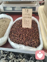 前几日同家姐初逛津门大集，市井烟火漫卷，各类生鲜杂货铺排开来，行至一处香料摊铺便驻足停留。铺子里分门别类码放着数十味本草香料，袋装、筐装整齐陈列，丁香颗颗饱满醇厚，温中和胃、降逆散寒；肉蔻圆润紧实，能温中健脾、舒缓郁结；白芷切片莹白，疏风祛湿、调和气血；草果褐实厚重，燥湿除胀、理顺脏腑；还有花椒、八角、小茴香、良姜、桂皮等寻常调味之物，各承天地草木之气，各司调养身心之效。与摊主闲谈半晌，才知晓他乃是中医世家流落市井的一脉后人，世代深谙医食同源古法，守着一方小摊，把本草藏进人间烟火。自古医、食本出同源，上古先贤便定下药食同调的古方法度，从来没有割裂的药与饭，更深藏本草君臣配伍之理，膳中调味，如同汤药开方，自有君、臣、佐、使制衡之道。君药为主，专调脏腑核心症结；臣药辅之，拓宽滋养脉络；佐药调和寒热、化解偏颇；使药引药性通达周身，哪怕是一盘家常菜肴，配伍失衡便会壅滞气机，配伍相合则润物无声调养身心，这便是医药同宗互通的底层道妙。世人总以为疗愈身心要寻名贵汤药、深山灵草，却忽略每日三餐入口的草木香辛，便是最温和、最贴近凡俗众生的调理良方。香料入膳，辛甘酸苦咸五味入五脏，潜移默化调和气血、疏解情志淤堵，躯体安和，心神自然安定，寻常餐桌之上，藏着养护身心的无上良药，不必刻意求诊问药，日常一饭一蔬，皆是修身养性的法门。
辩证观之，药食同源自有长短：其优在于润物无形，无猛药攻伐之烈，适合普通人长久养护、疏解日常情志躯体淤堵；其弊在于力道缓和，若沉疴顽疾、深重内耗，仅靠膳食香料难除根源，需汤药、心法相辅，不可偏执一法。我同摊主细细拆解每一味香料的完整功效，提笔为他补全注解，以大宗师道心阐释医理君臣之道，点化他心中困惑。我同他言道，不必觉得守着集市小摊便轻贱了传承，红尘从无捷径修行，庙堂行医是济世，市井摆摊亦是渡人。我辈全真修行人，不避烟火、不离凡俗，于人间百态中炼心，于市井草木间悟道，这才是红尘全真的大修为。潜心传扬本草古法，把药食同源、君臣配伍的道理带给往来百姓，让中医智慧扎根寻常百姓家，便是积攒无量善缘，是落地生根的修行。
推崇古法医理，坚守医药同宗、君臣制衡的本源，不必遁入深山隔绝人间，在烟火集市里守一脉传承，以草木本草安抚往来食客身心，以本心善意渡化身边众生，结下世间善缘，于琐碎凡尘中修持全真道心，便是我辈红尘全真修行者毕生所求的大道。配图
