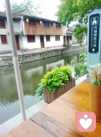 河水悠悠，时光也跟着慢了下来。
坐在黄酒小镇的河边，一碗热面，几声流水，
把紧绷的神经，都泡进江南的软风里。
原来最奢侈的放松，不过是偷得半日清闲，
看水波晃，看云影摇，让心跟着慢下来。配图