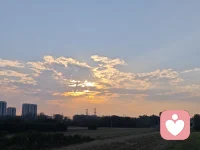 举着手机拍了半天，总觉得镜头里的夕阳差了点意思。
等抬眼望过去才明白，金红的光把云边烘得软软的，斜斜落在远处的楼、树尖和田埂上，连吹过来的风都跟着慢了下来。这一路走了这么多沟坎才懂，那些装不进镜头的温柔，都是岁月悄悄递过来的答案，不用急着拍下来——你站在光里，就已经接住了。